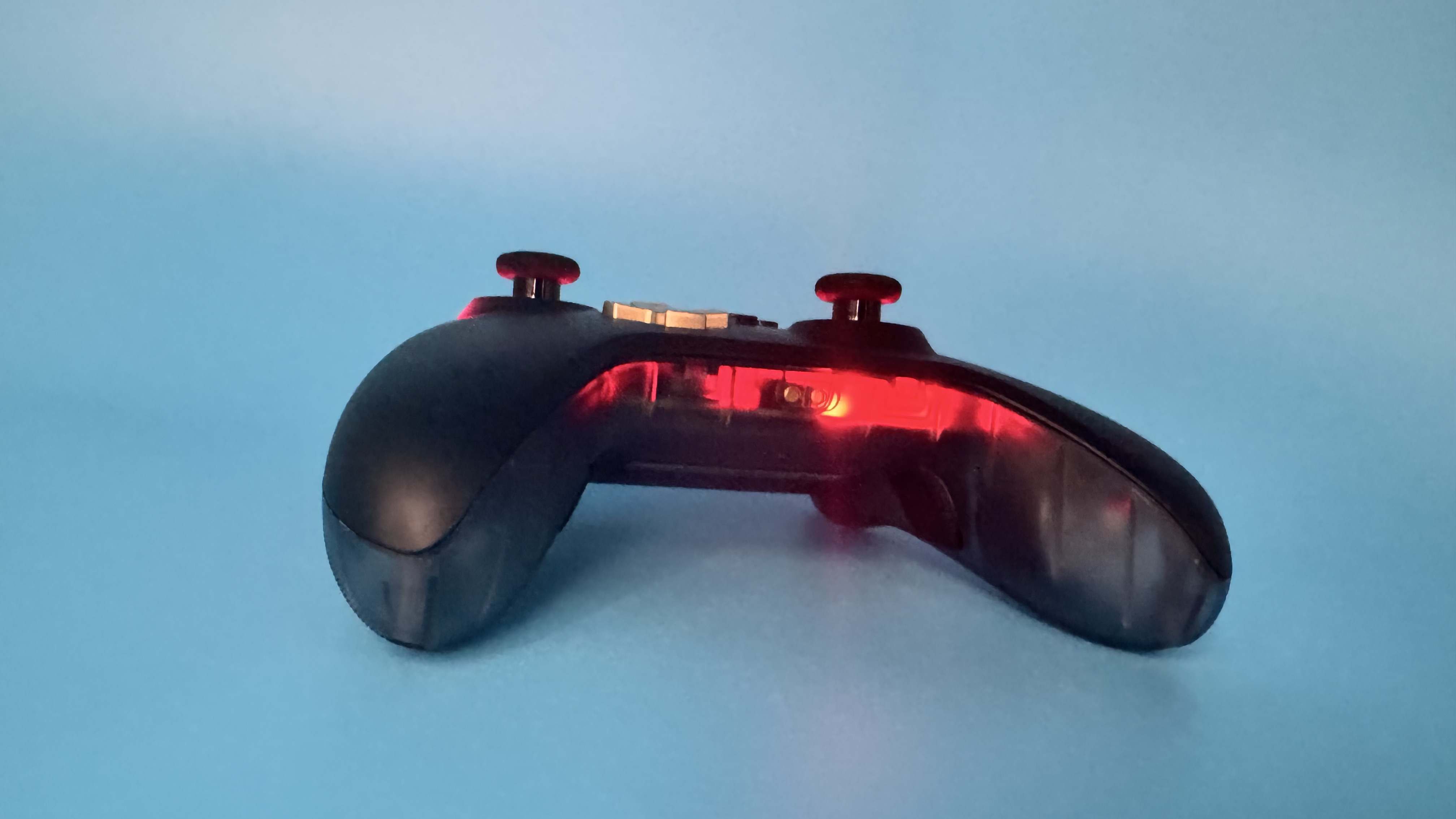 The bottom of EasySMX D05 black gaming controller (with red RGB on) on a blue background