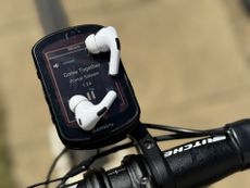 A pair of Apple AirPods Pro 2 sitting on a Garmin 840 and showing the muisc screen