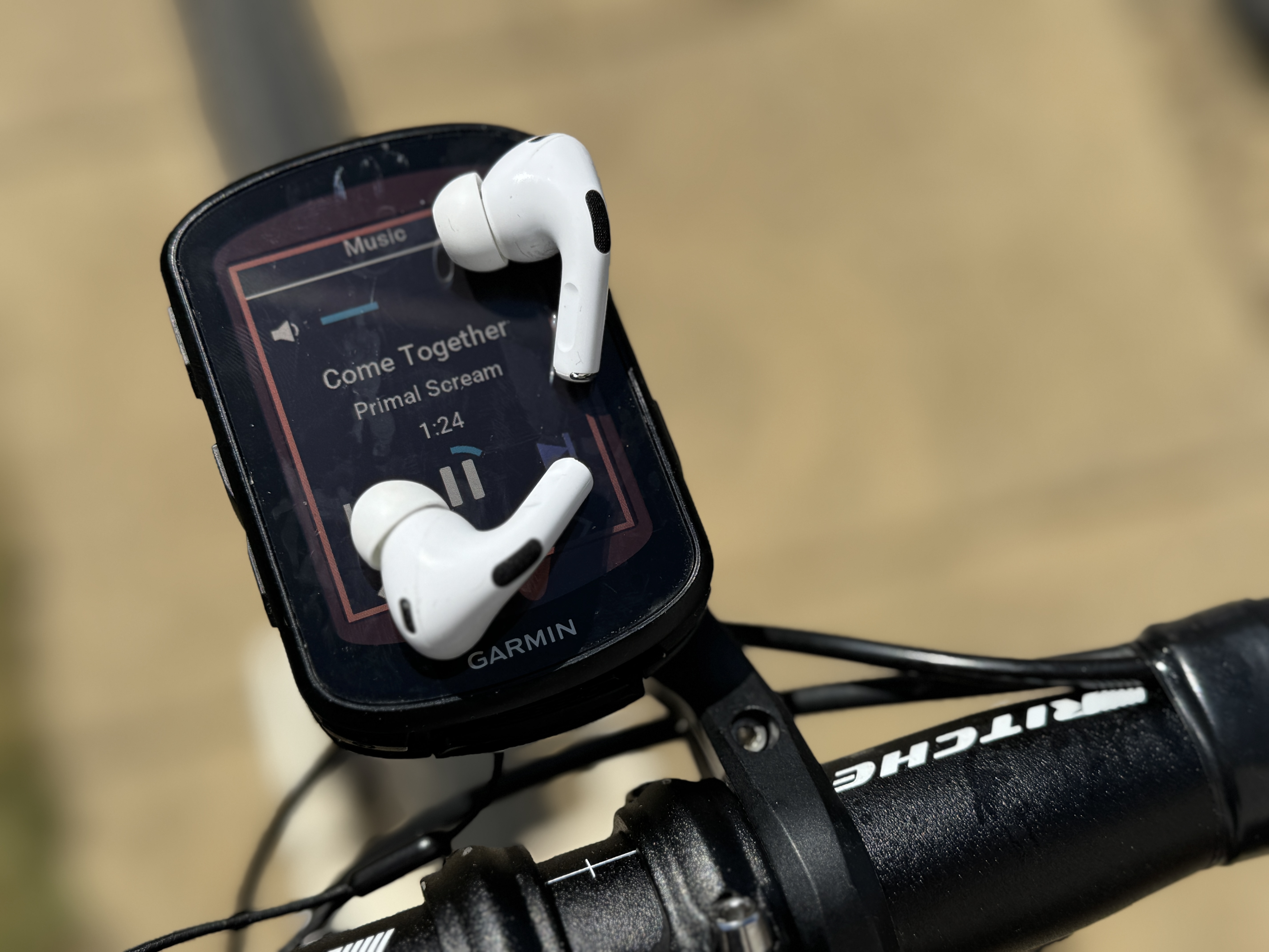 A pair of Apple AirPods Pro 2 sitting on a Garmin 840 and showing the muisc screen