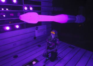 NASA engineer Nettie Roozeboom examines a glowing pink rocket model under a blue light in NASA's Ames Research Center.