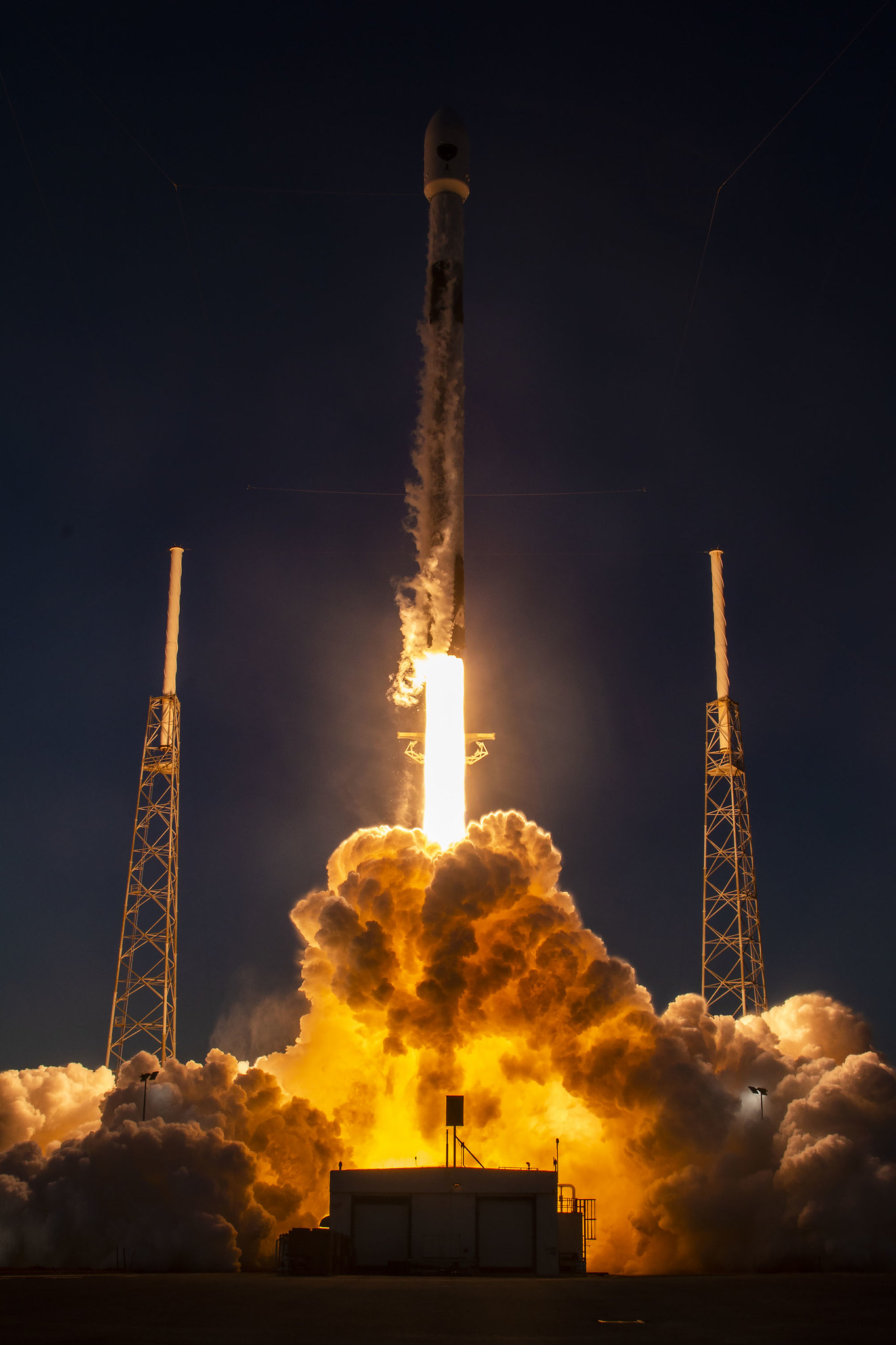 close up view of a rocket launching in shadow with bright plumes of steam underneath