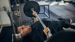 Man performing a bench press with.a barbell using a narrow grip