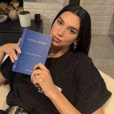 Dua Lipa wears a black T-shirt, black high-waisted pants, and a Chrome Hearts belt