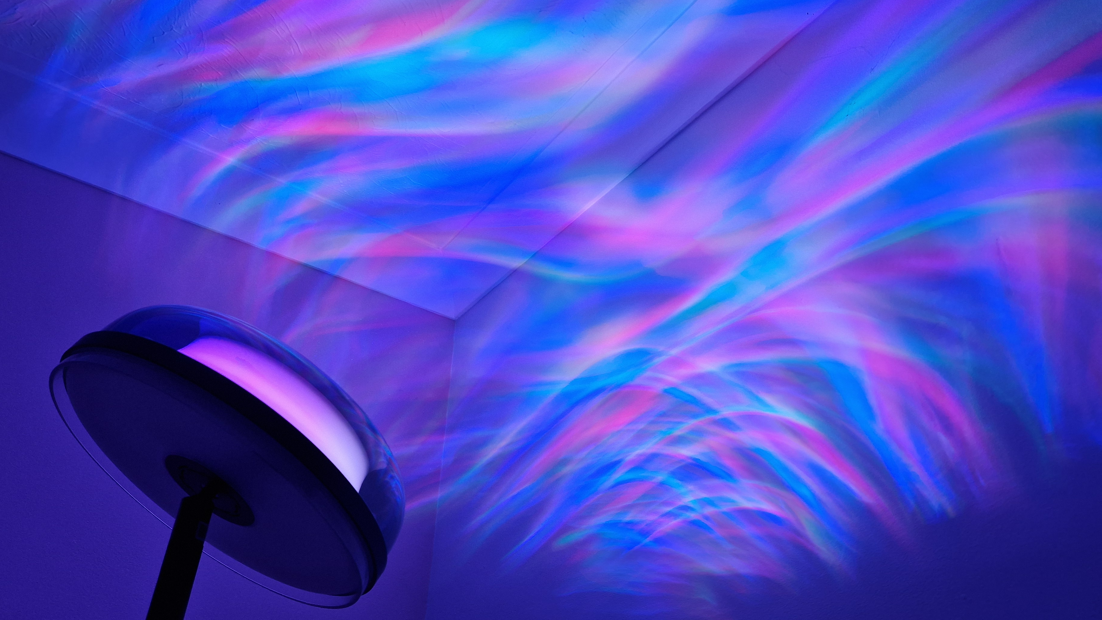 The Govee Uplighter Floor Lamp is projecting swirls of colour onto a bedroom wall and ceiling.