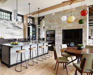kitchen with gray cabinets and island, barstools and dining area with round table and green chairs and colored lights