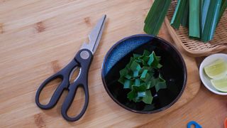 Scissors on a kitchen worktop beside some leeks and a bowl