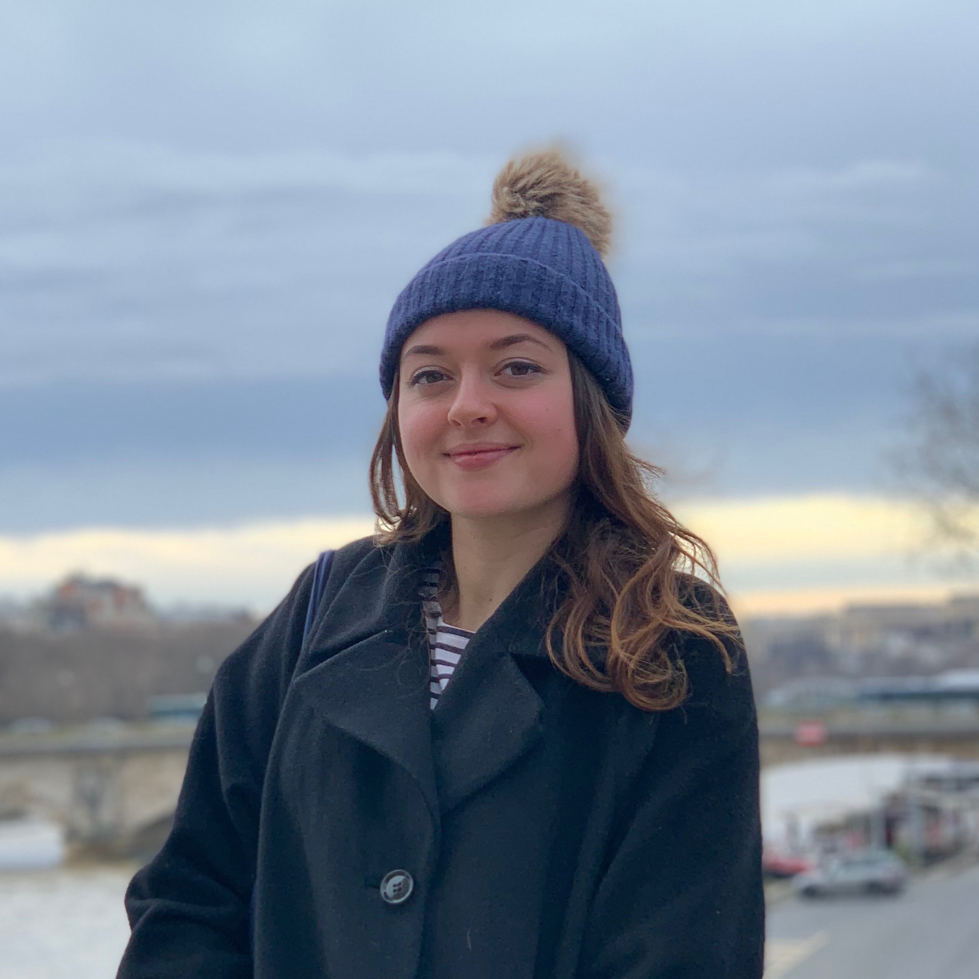 lauren wearing a wooly hat and coat in front of a wintery backdrop