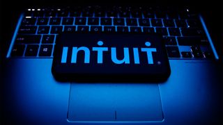 Intuit logo and branding pictured on a smartphone screen placed on top of a laptop keyboard