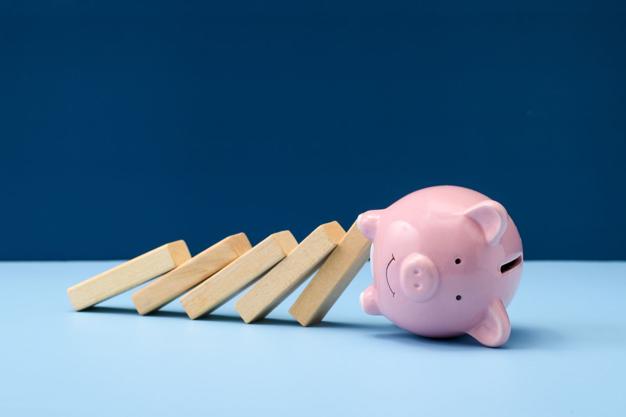 Piggy bank knocked over by dominoes