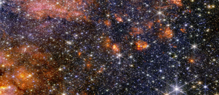 A photo full of stars in deep space with orange and pink clouds of dust swirling around.