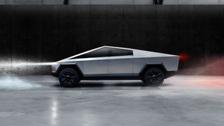 The side-profile of the futuristic Tesla Cybertruck sitting in a warehouse