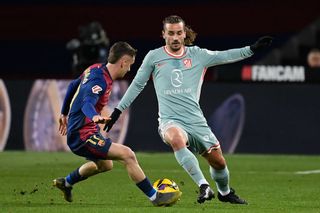 Atletico Madrid's French forward #07 Antoine Griezmann (R) is challenged by Barcelona's Spanish midfielder #17 Marc Casado during the Spanish league football match between FC Barcelona and Club Atletico de Madrid at the Estadi Olimpic Lluis Companys in Barcelona on December 21, 2024.