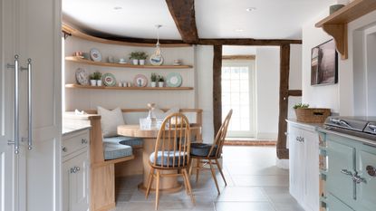 banquette seating small corner of open plan kitchen with pink white and green artwork which defines the scheme of the green banquette pink and white striped cushions