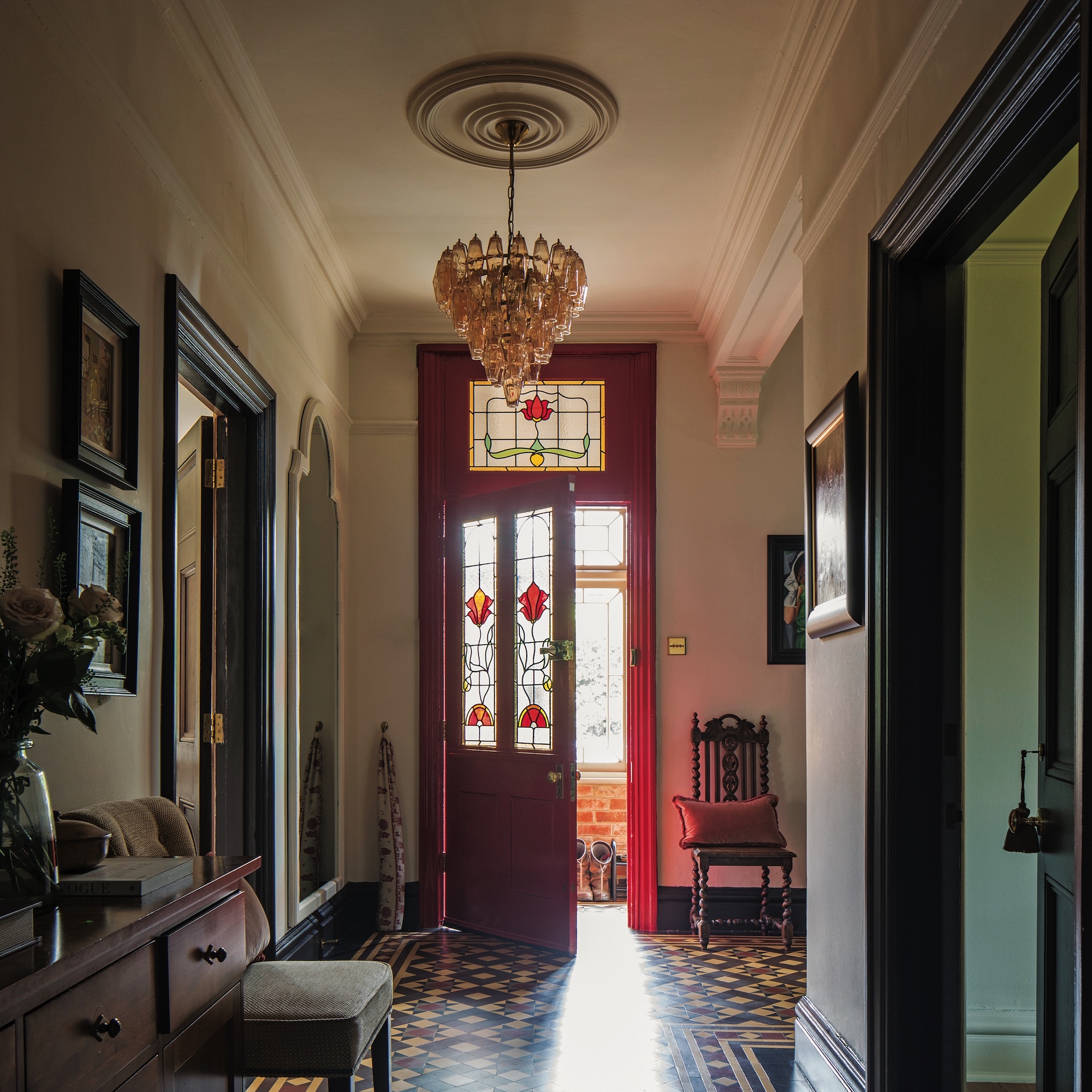hallway in Edwardian house with high ceiling, original Minton floor tiles and stained glass interior door painted red