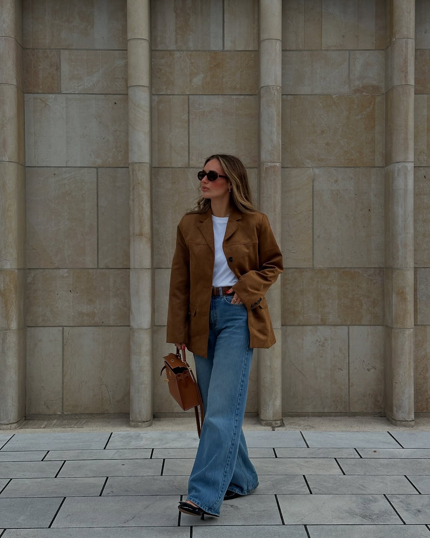 Influencerin trägt Wildlederblazer, weite Bluejeans und Ballerinas