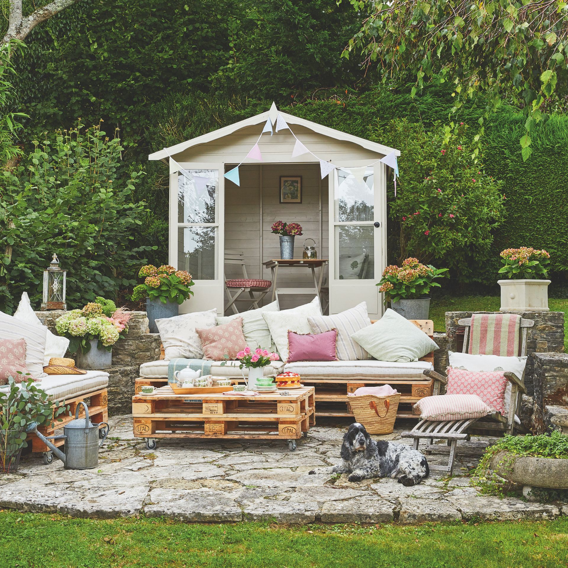 garden with outdoor living area, furniture made from pallets, shed in background