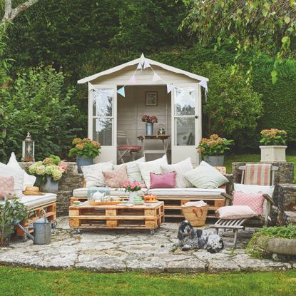 garden with outdoor living area, furniture made from pallets, shed in background