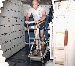 NASA astronaut Bill Thornton working with the treadmill he invented for use aboard the space shuttle.