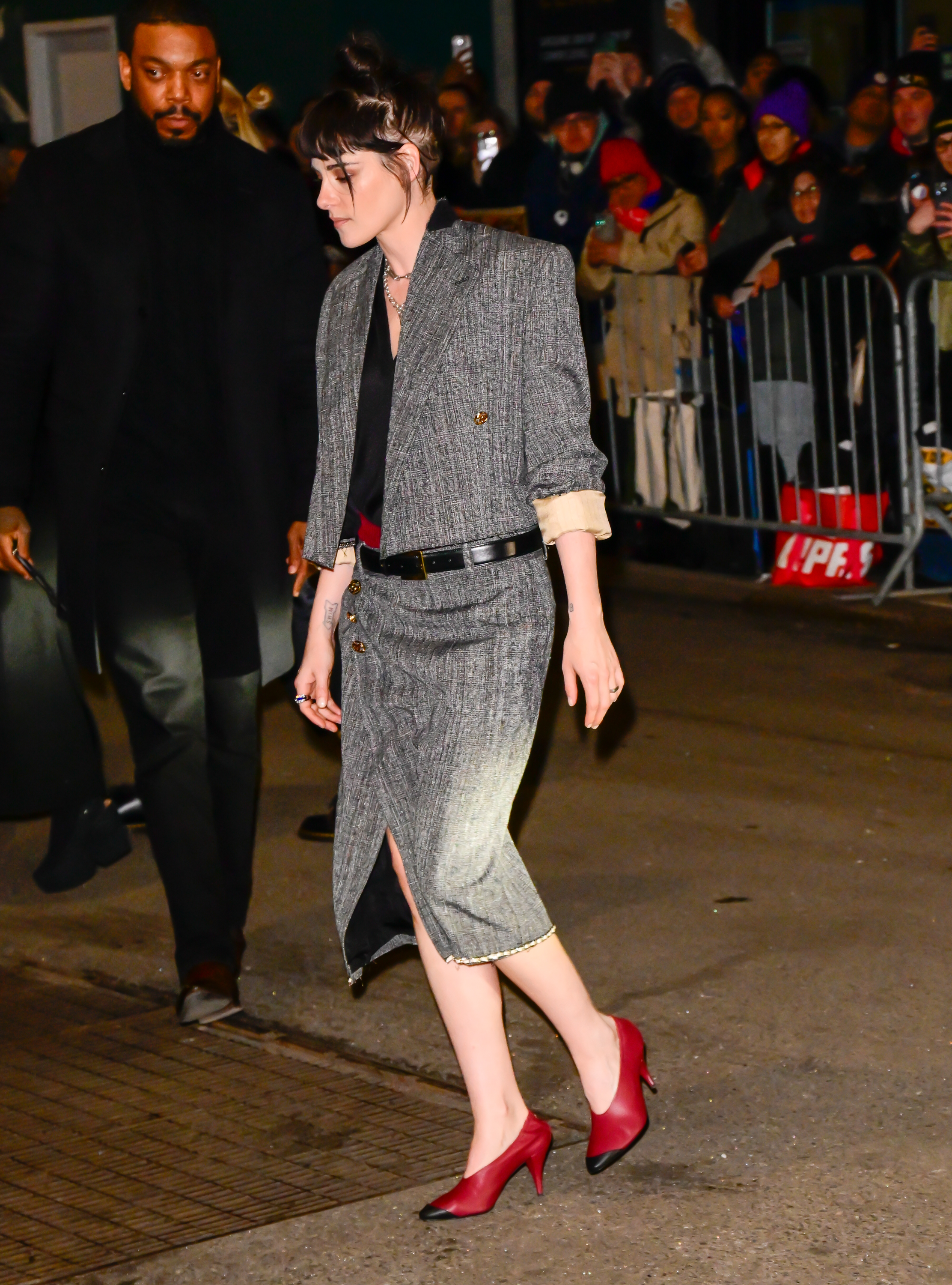 Kristen Stewart wears a grey two piece with red two-tone cone heel shoes.