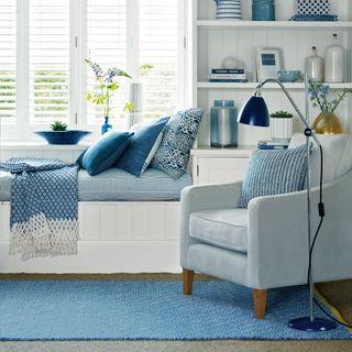 living room with white shelf window blue sofa chair with cushion and standing lamp