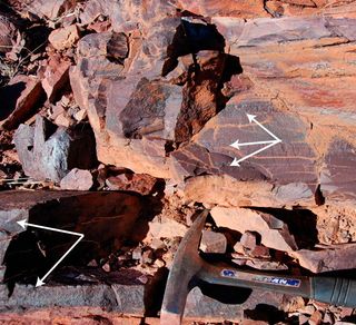 Manganese-enriched deposits (indicated by white arrows) in Koegas iron formation from the Rooinekke Mine section.
