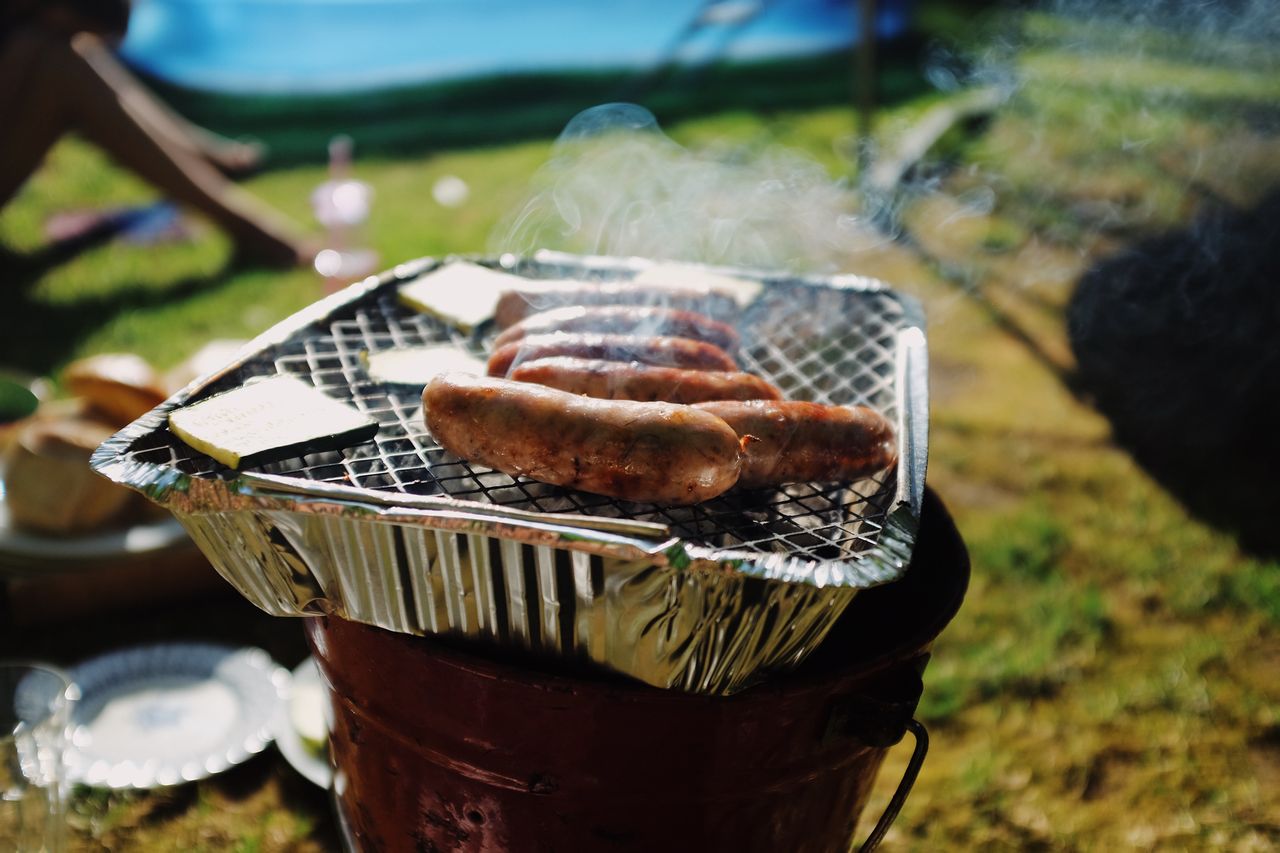 Sausages on disposable BBQ in back garden