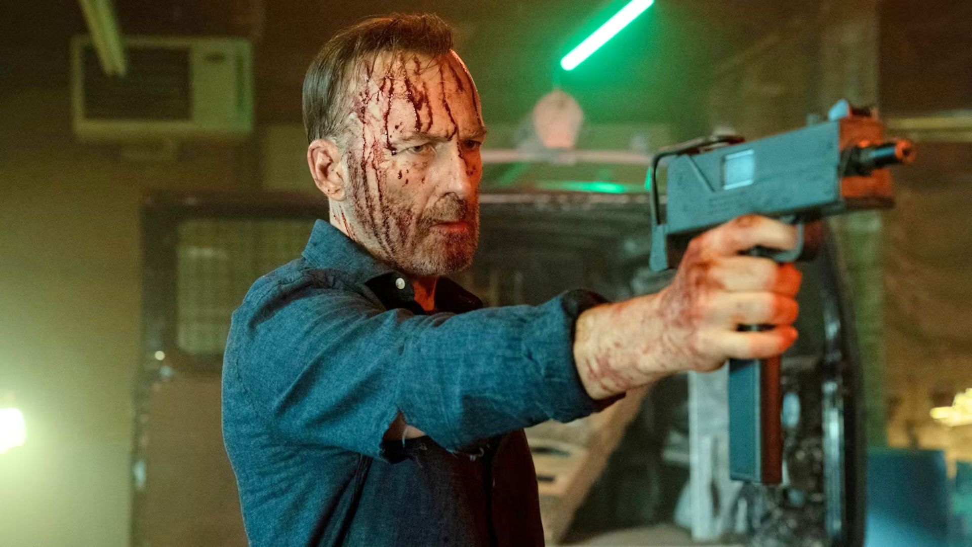 Bob Odenkirk spattered with blood holding a gun