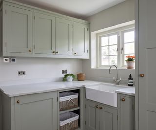 sage green utility room with white butler sink beneath window