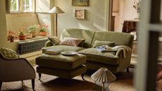 A sitting room with an olive green sofa and soft furnishings