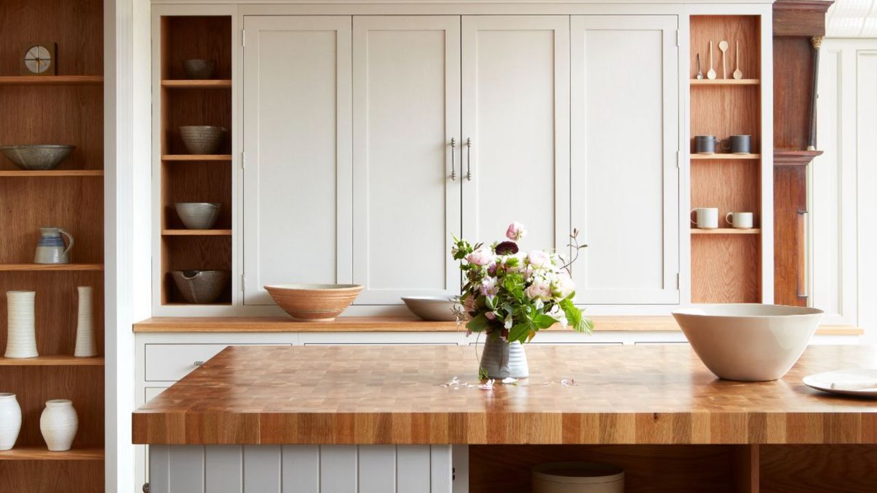 kitchen countertop trends, kitchen with cream painted custom cabinetry, open shelving, wooden countertops and thick wooden countertop on kitchen island, earthenware bowls, vase of flowers 