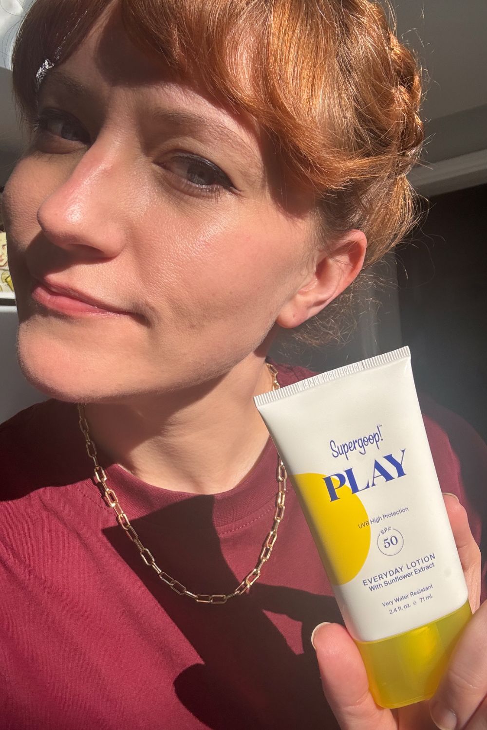 a headshot of matilda with a tube of supergoop play spf lotion