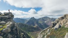 man stands on rock looking down into valley on the Isle of Arran