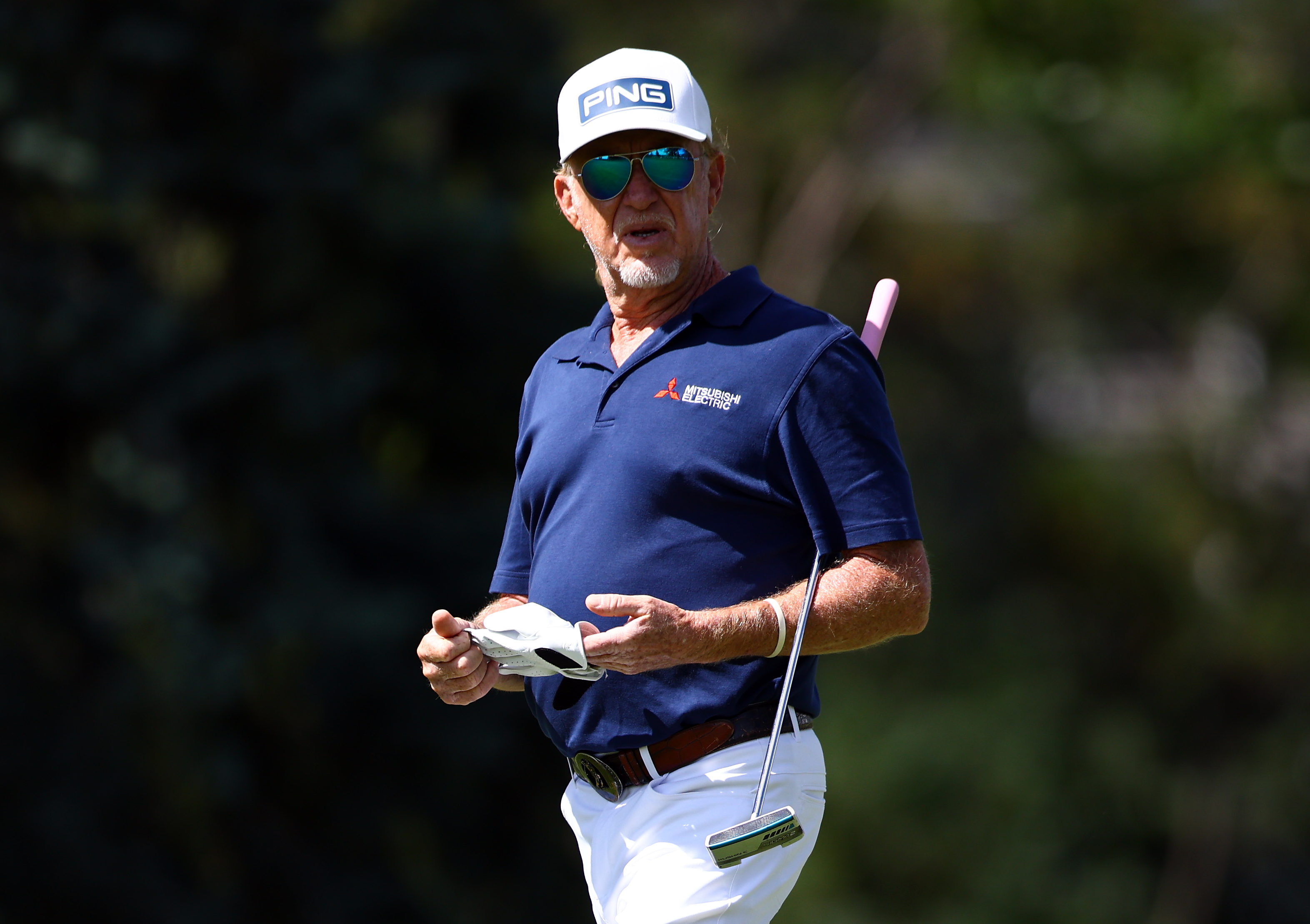 Miguel Angel Jimenez walks off the green holding a putter
