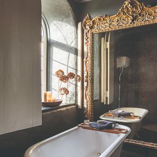A bathroom with a large gilded mirror and a bathtub