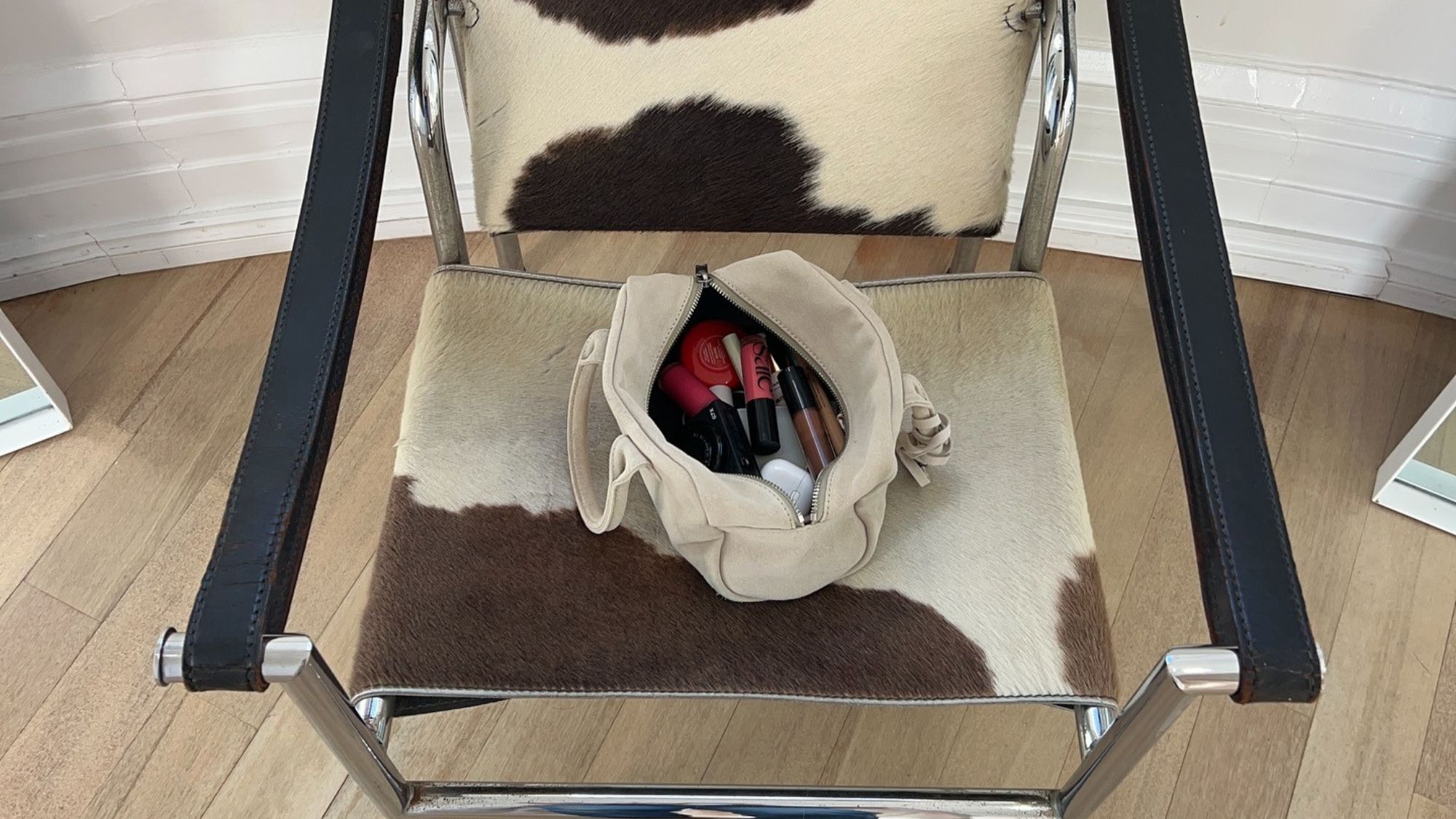 An image of a makeup bag full of products sitting on a chair.