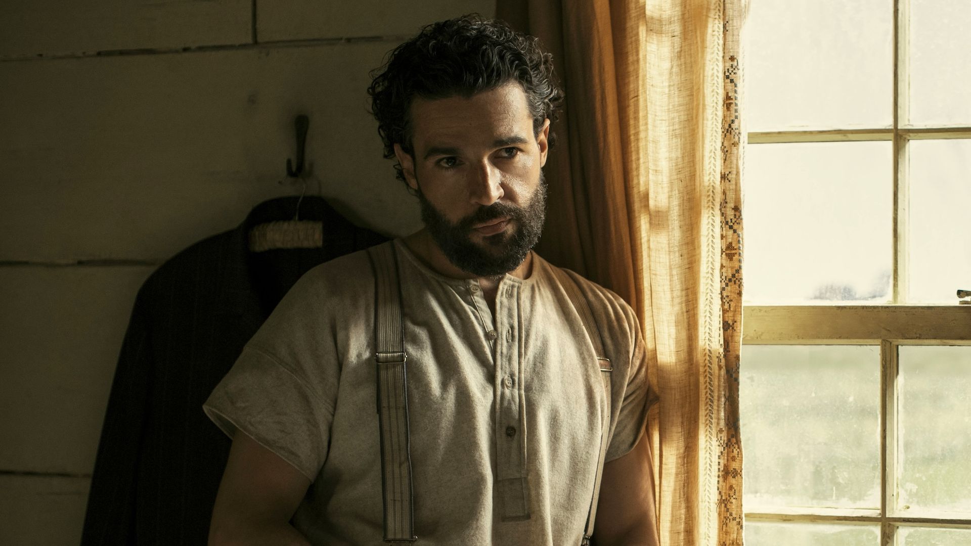 Chris Abbott as Adam Trask standing next to a window in East of Eden