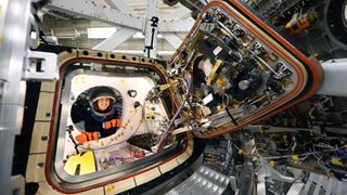 NASA astronaut Christina Koch, an Artemis 2 mission specialist for the moon mission, tests the side hatch of an Orion spacecraft at Lockheed Martin Space in Denver. The Orion spacecraft set to carry Koch and three others around the moon finished a power-on test at NASA's Kennedy Space Center on Nov. 6, 2023. 