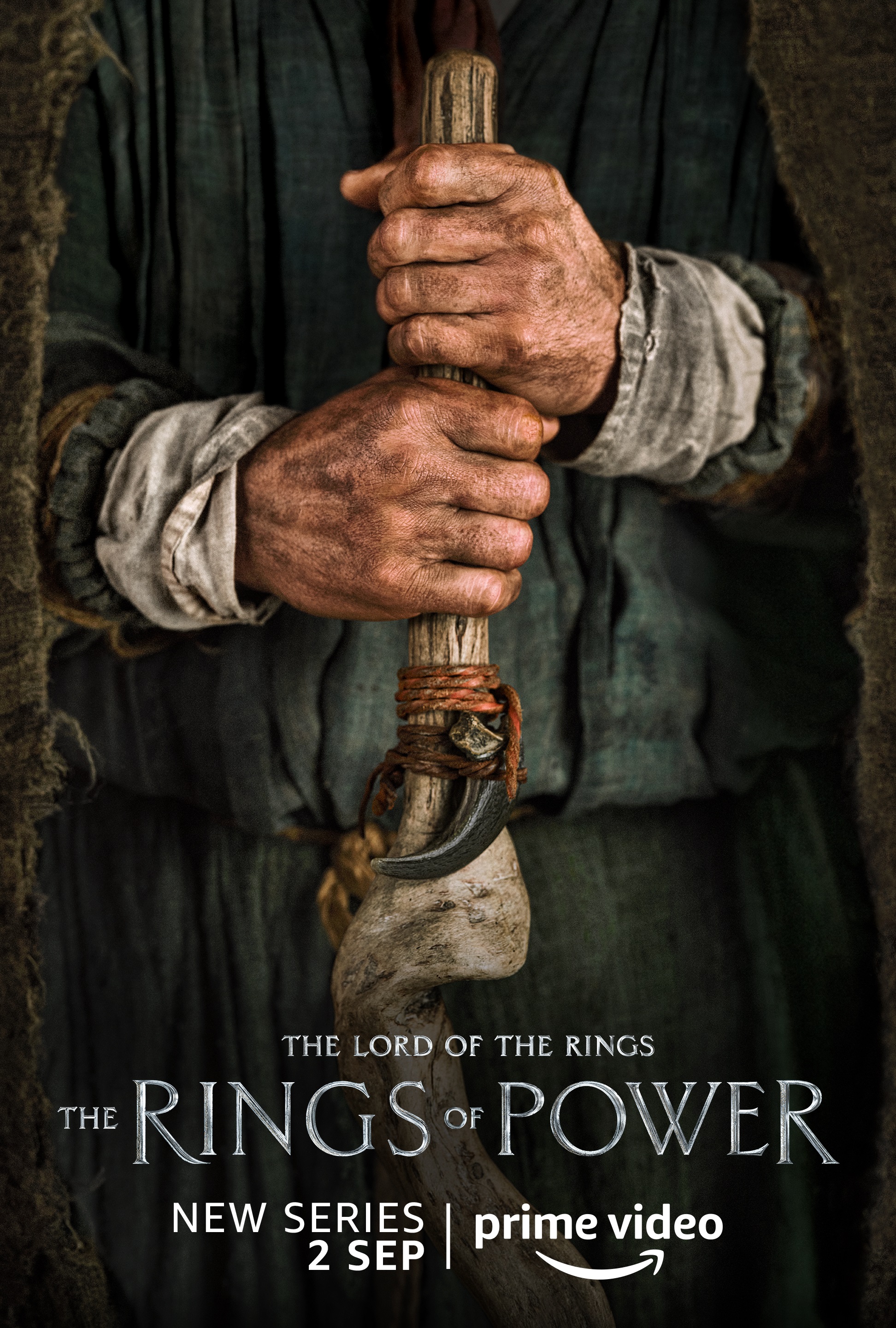 A person holding a club character poster for Lord of the Rings: The Rings of Power