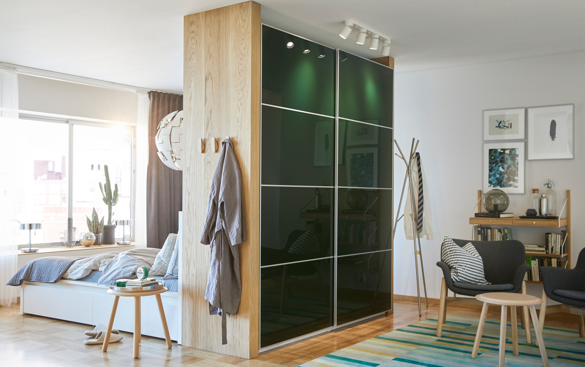 A bedroom divided into a dressing room with a Pax wardrobe with green Hokksund sliding doors