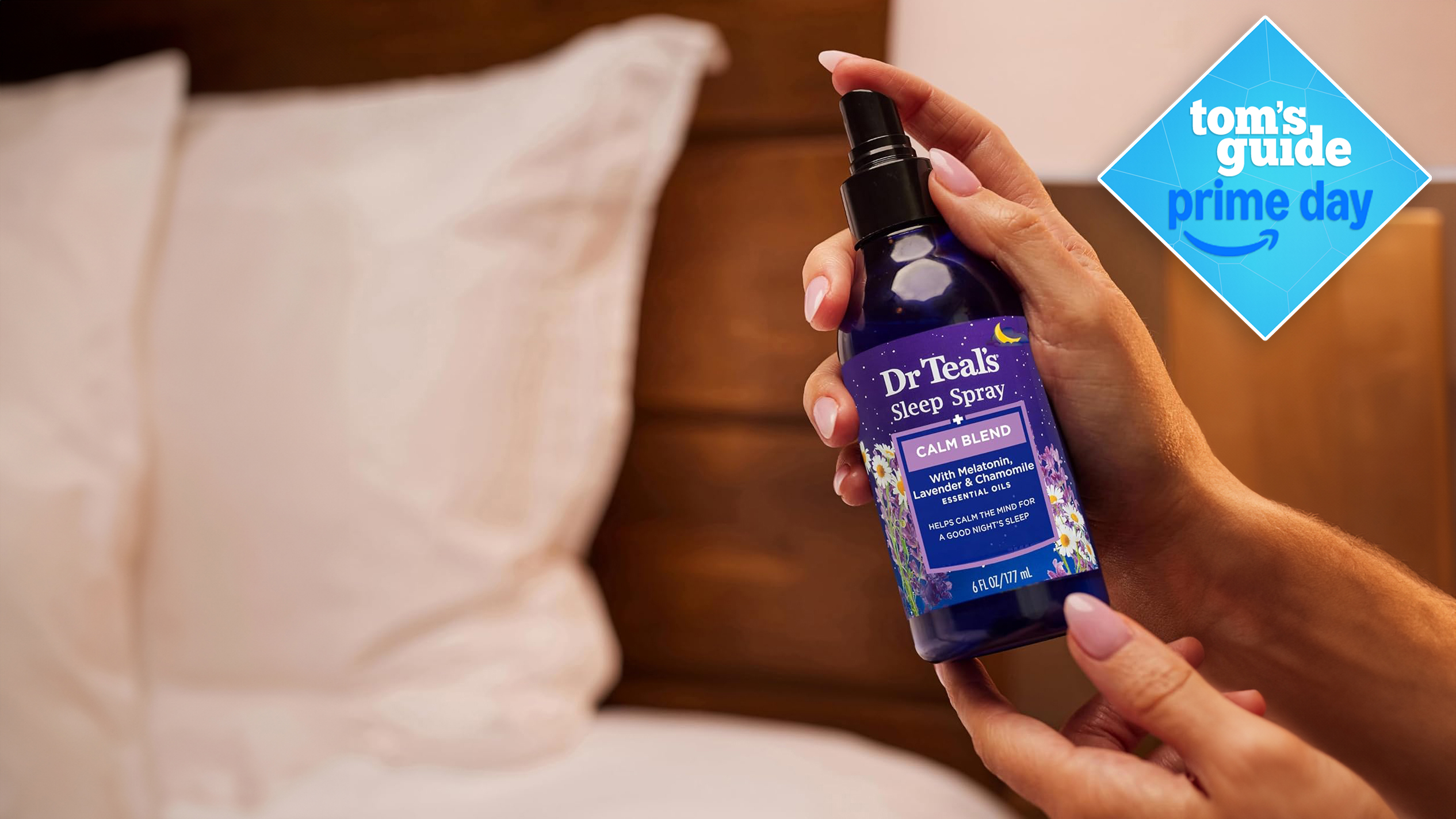 Woman holding a bottle of Dr Teal's Calm Blend Sleep Spray for Pillows and Bed Sheets next to two white pillows on a bed she is about to spray