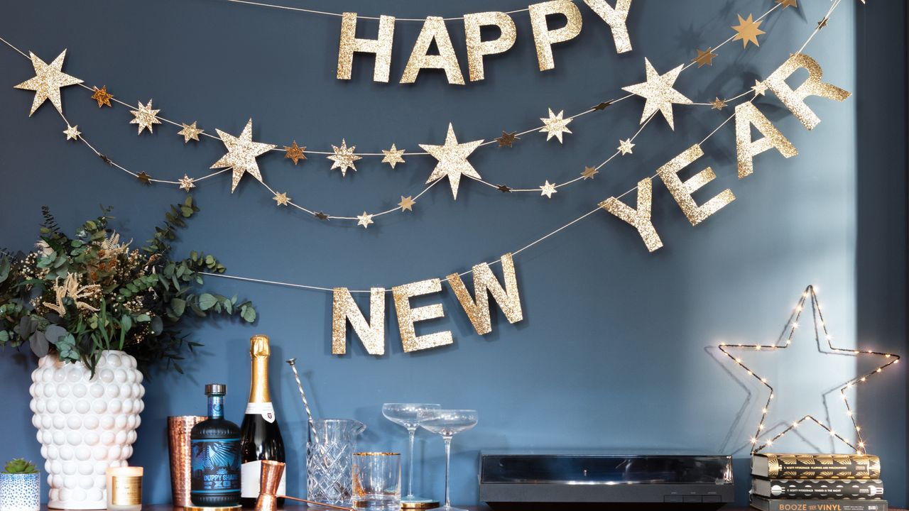 A blue-painted living room decorated with a New Year&#039;s Eve bunting, drinks set up on the sideboard and decorated with a star-shaped light