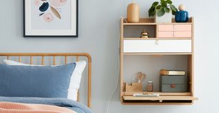 pale blue bedroom with wooden frame bed with wall mounted storage unit in place of a bedside table to support professional decluttering methods