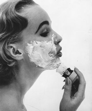 A woman applies shaving cream in a photo from Housewife Magazine, 1956.