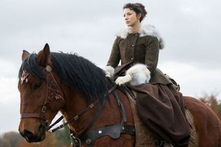 Caitriona Balfe sitting on a horse in in scene from 'Outlander'