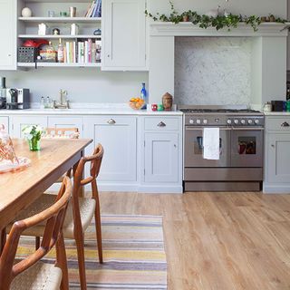 blue kitchen units with wooden floorboards and rug