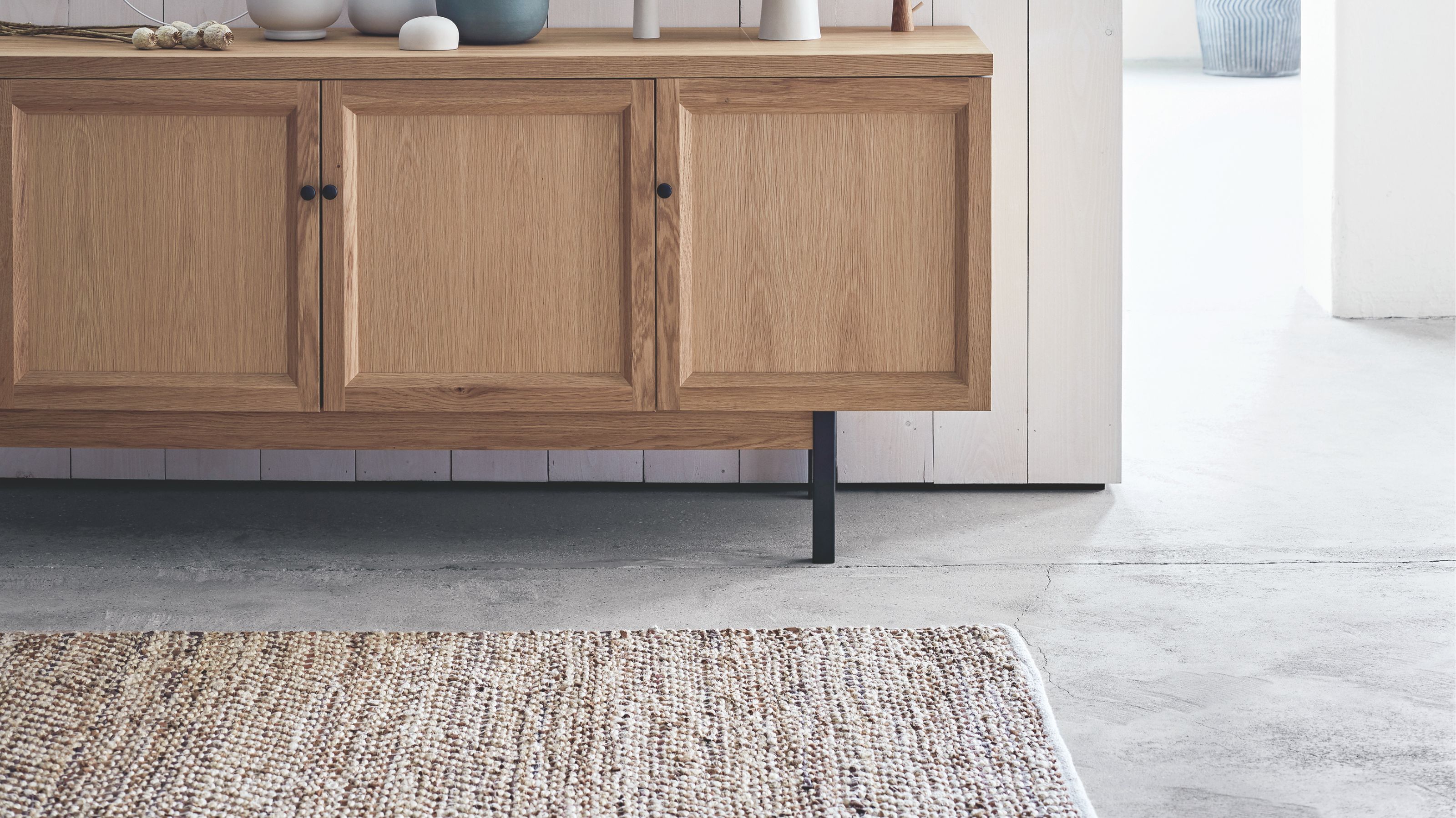 Polished concrete flooring with wooden sideboard and neutral textured rug