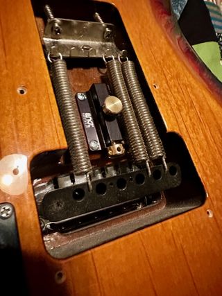 A photo of an Engl Hardtailer. The device allows a guitarist to block a tremolo unit when desired by pushing the Hardtailer into position and preventing the tremolo unit from moving. When inactive (as shown in this photo), the Hardtailer has no involvement with your guitar, and you’ll barely notice it’s there.