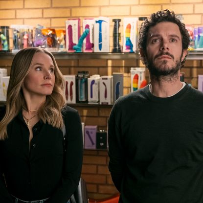 Kristen Bell as Joanne and Adam Brody as Noah, standing in front of a wall of sex toys, in episode 106 of Nobody Wants This.