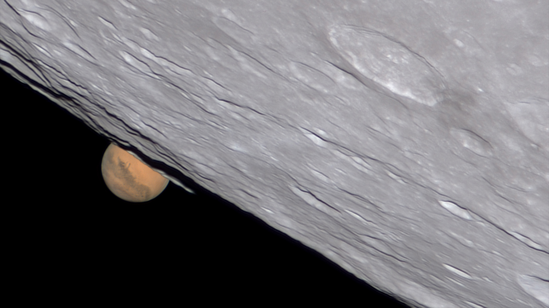 Mars peaks over the surface of the moon.