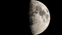 The moon is photographed with its right side lit by sunlight in a black night sky.